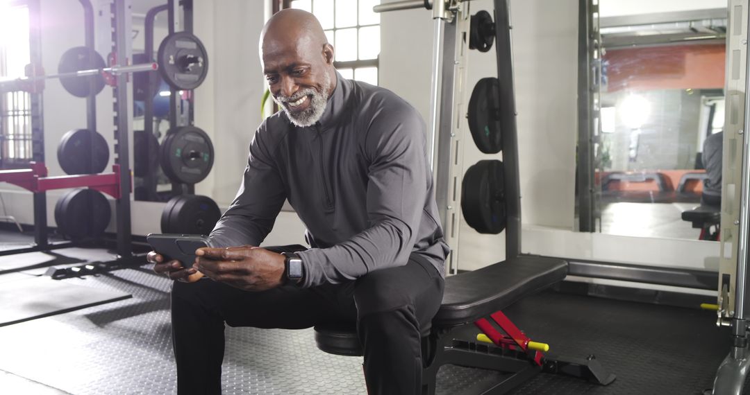 Senior Man Enjoying Smartphone Break in Gym Setting
