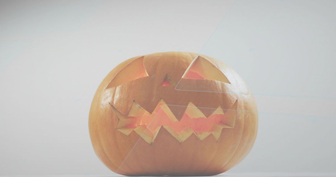 Glowing carved jack-o'-lantern casting warm light on minimal gray tabletop