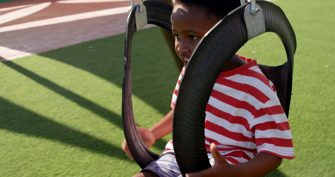Happy Child Swinging on Playground Tire Swing