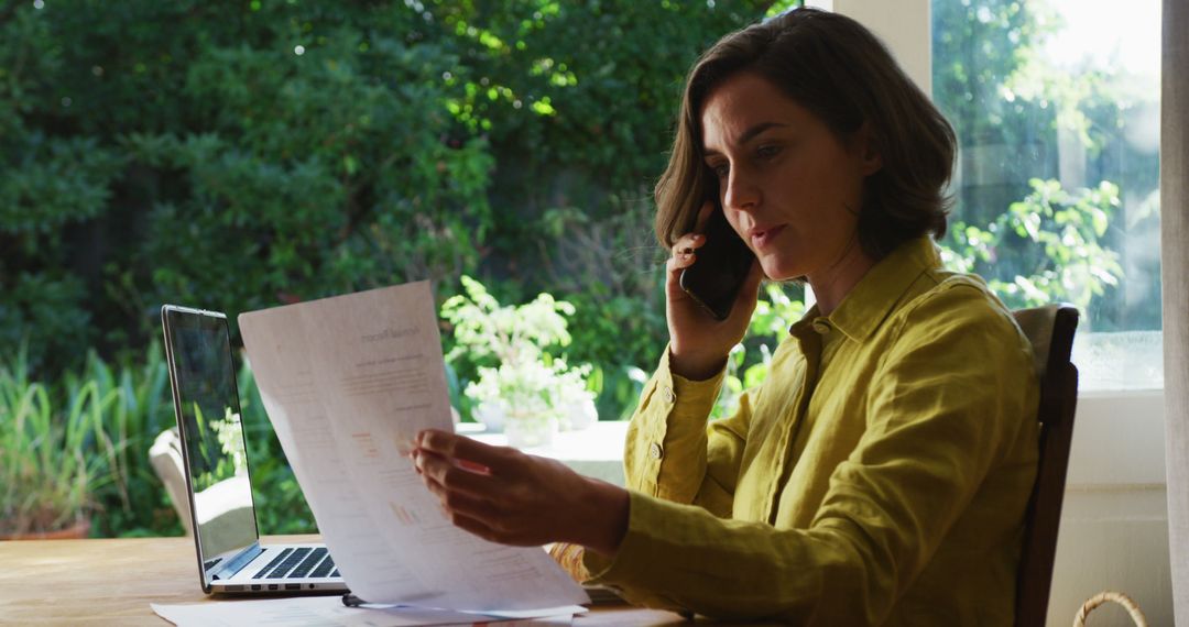 Woman Analyzing Financial Documents While on Phone Call - Free Images, Stock Photos and Pictures on Pikwizard.com