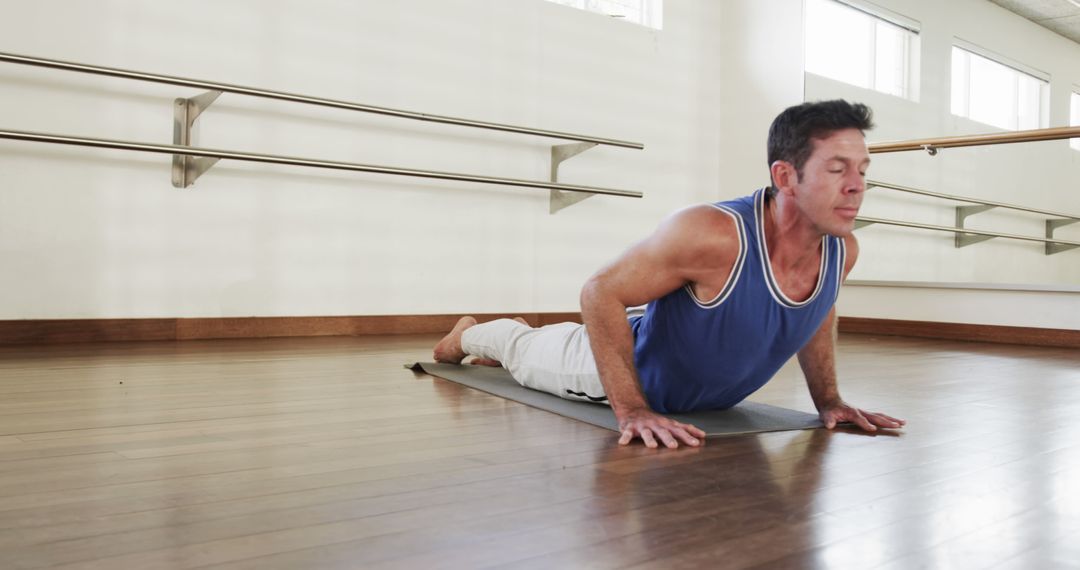 Middle-Aged Man Practicing Yoga Stretch in Dance Studio - Free Images, Stock Photos and Pictures on Pikwizard.com