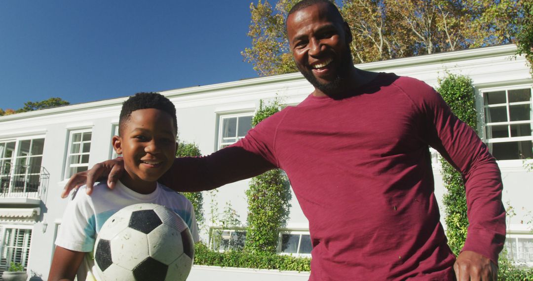 Portrait of african american dad and son smiling while holding a football in the garden - Free Images, Stock Photos and Pictures on Pikwizard.com