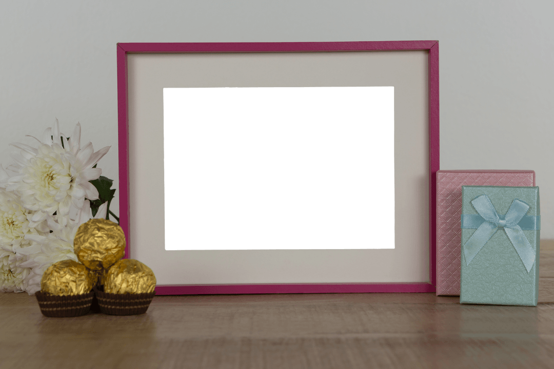 Transparent Photo Frame with Flowers, Chocolates, and Gift Boxes on Table