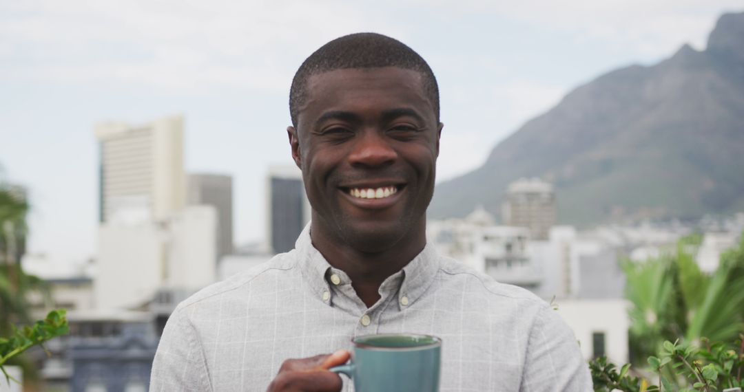 Smiling man with coffee cup enjoying city rooftop - Free Images, Stock Photos and Pictures on Pikwizard.com