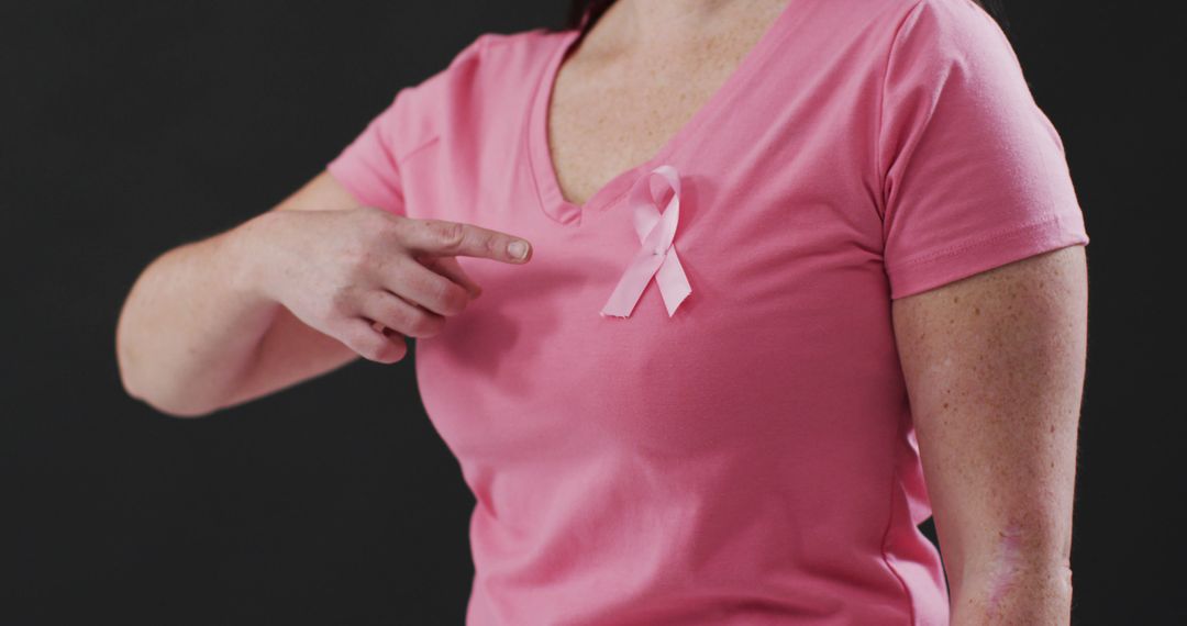 Woman Pointing at Pink Ribbon on Shirt for Breast Cancer Awareness - Free Images, Stock Photos and Pictures on Pikwizard.com