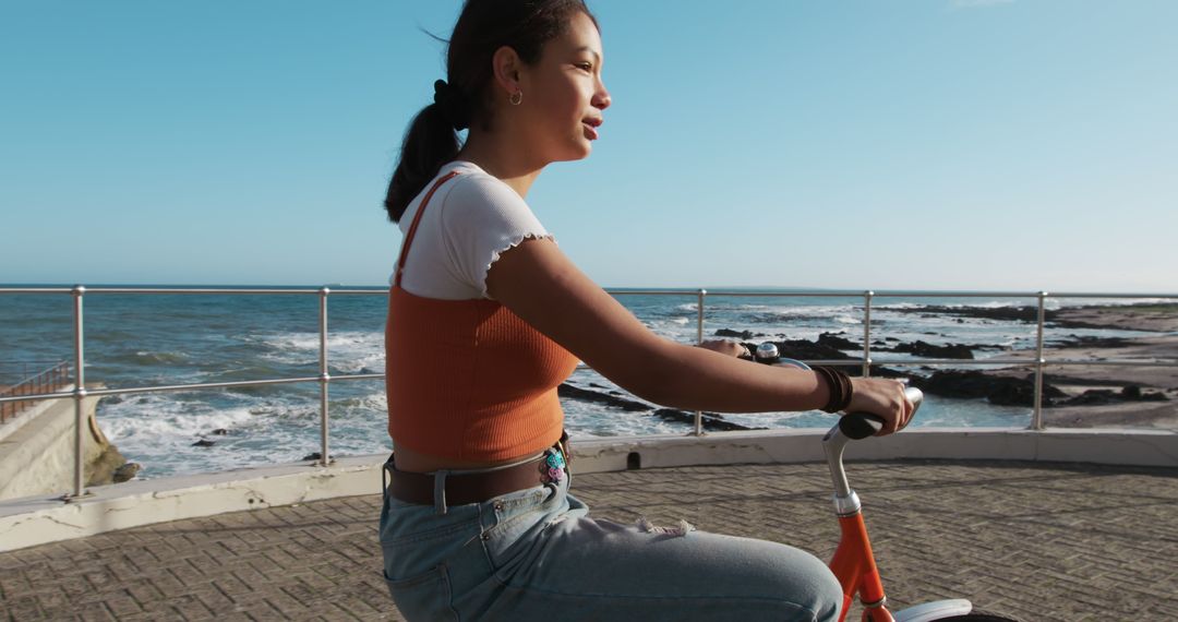 Young Woman Cycling Along Beachside Promenade - Free Images, Stock Photos and Pictures on Pikwizard.com