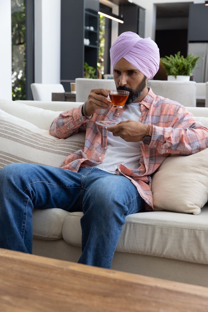 Man with Turban Relaxing on Sofa while Enjoying Tea