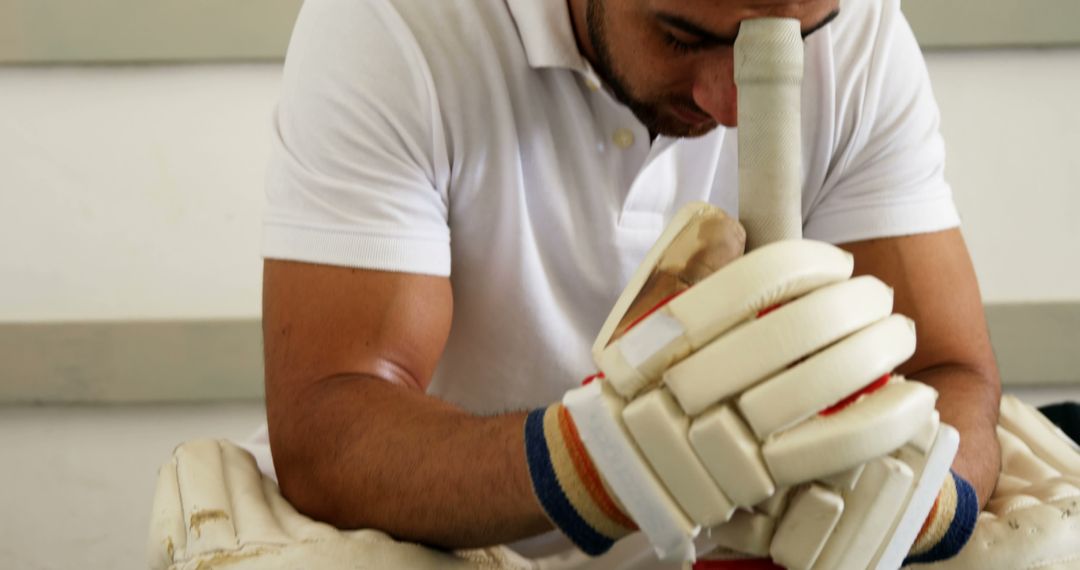 Cricketer Kneeling with Bat in Dressing Room Expressing Deep Thought - Free Images, Stock Photos and Pictures on Pikwizard.com