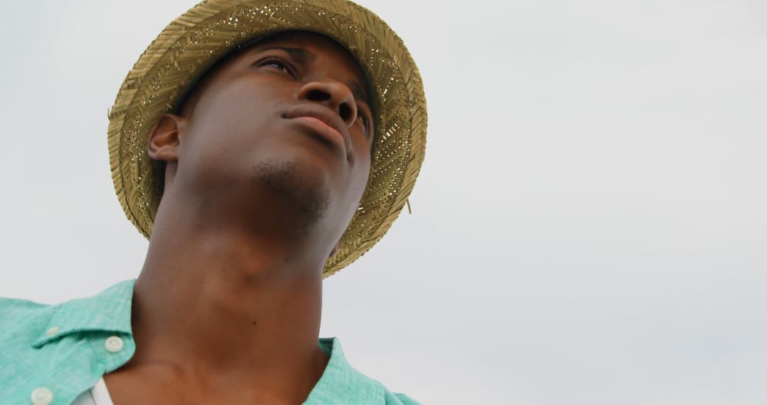 Confident Man in Straw Hat Gazing Into Horizon on Beach