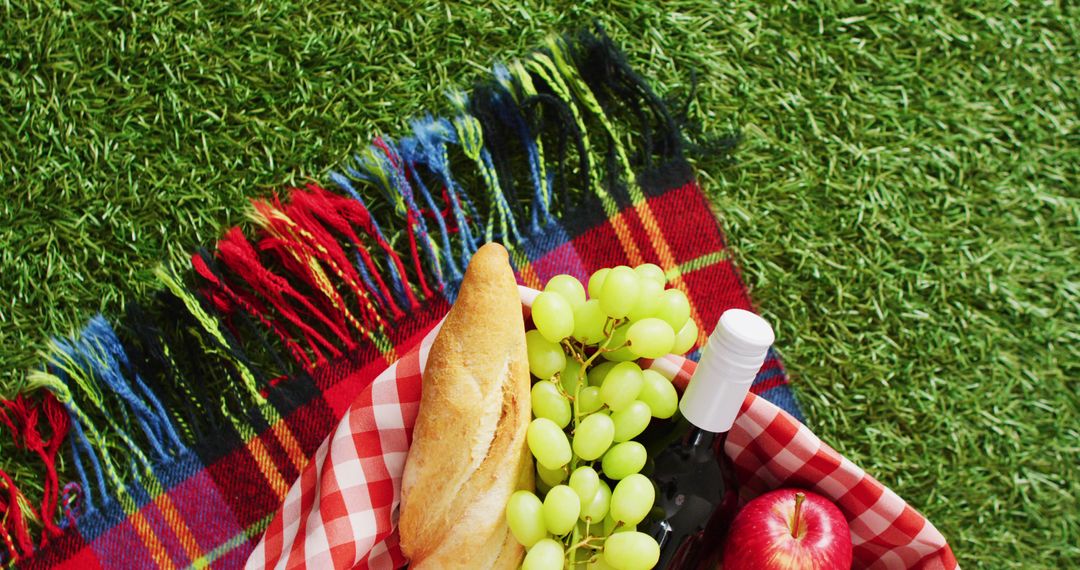 Picnic basket with checkered blanket, fruits, bread and wine on grass with copy space - Free Images, Stock Photos and Pictures on Pikwizard.com