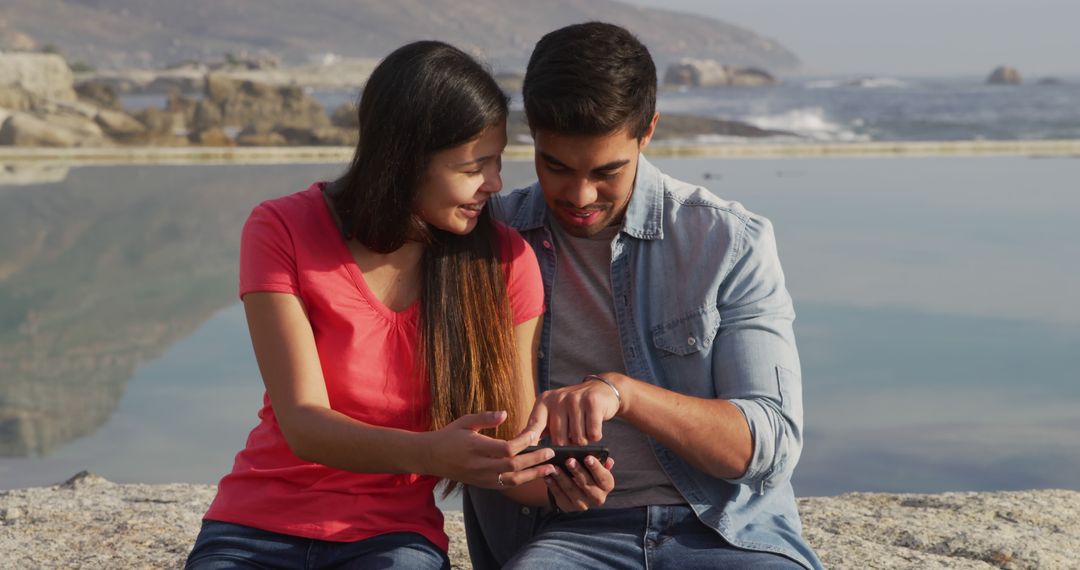 Happy Couple Relaxing by Sea and Using Smartphone