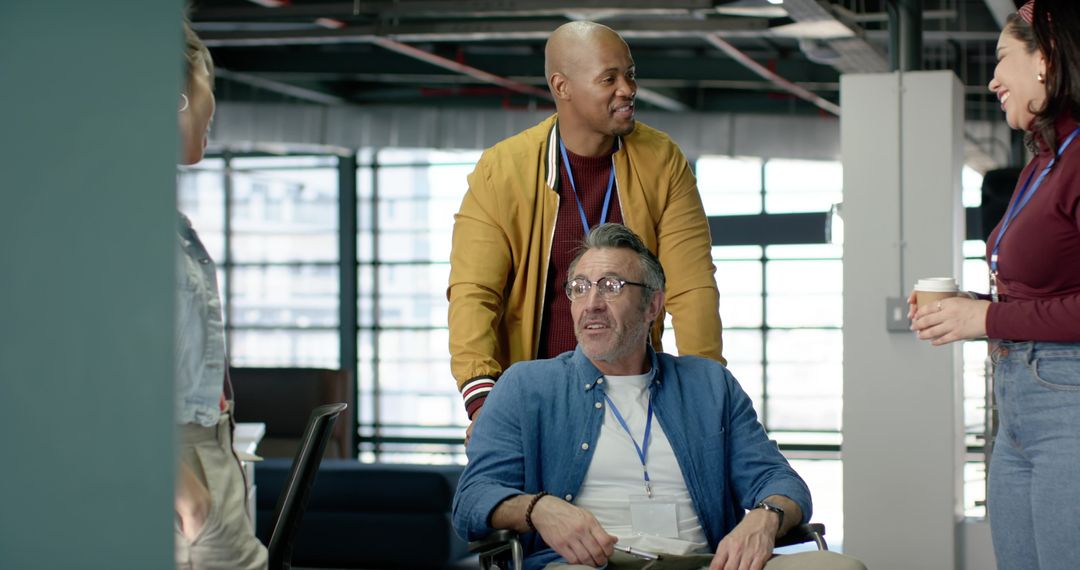 Inclusive coworker team supporting colleague in wheelchair, sharing coffee and conversation in moder