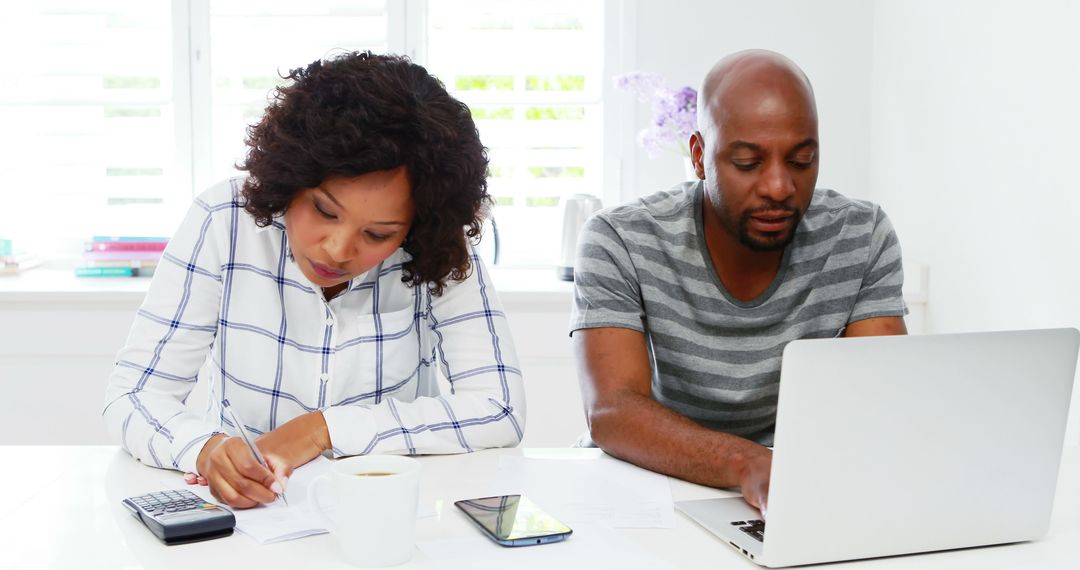 Couple Budgeting Together at Home with Calculators and Laptop - Free Images, Stock Photos and Pictures on Pikwizard.com