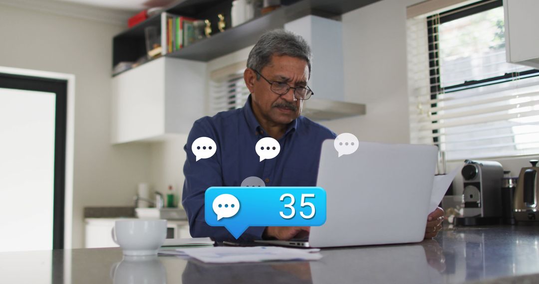 Man Receiving Notifications on Laptop in Modern Kitchen