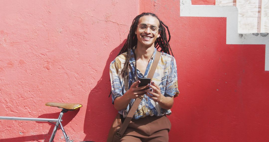 Happy Person With Dreadlocks Using Smartphone Against Red Wall - Free Images, Stock Photos and Pictures on Pikwizard.com