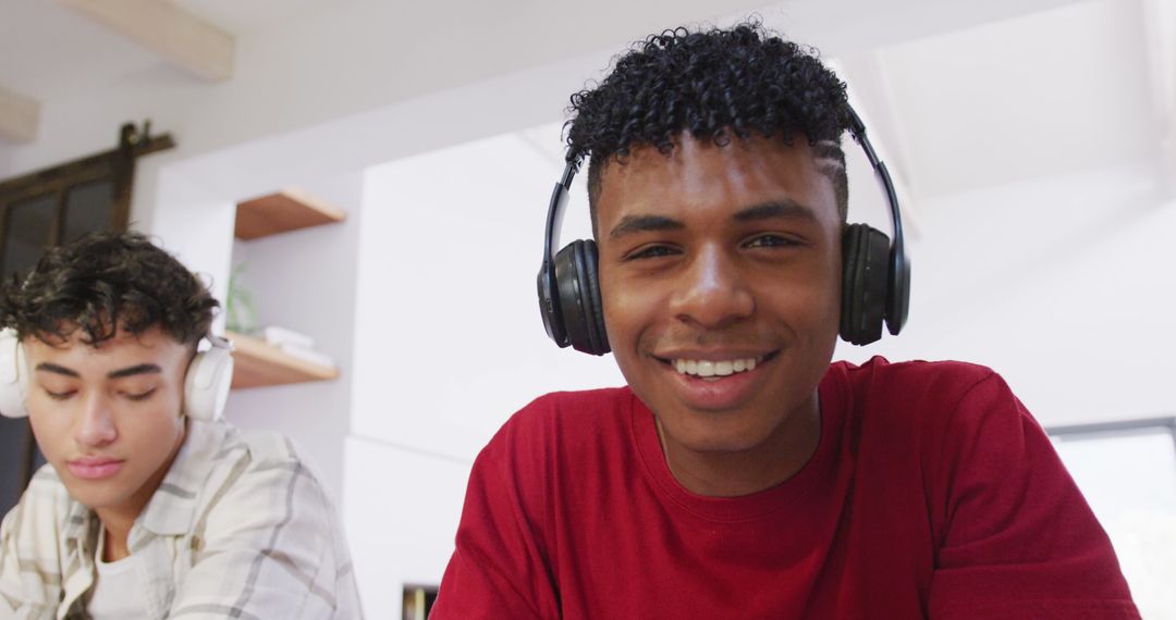 Two Young Men Using Headphones and Smiling While Working Indoors - Free Images, Stock Photos and Pictures on Pikwizard.com