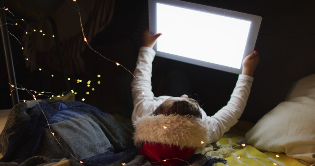 Child Using Tablet in Dark Room with Festive Lights - Free Images, Stock Photos and Pictures on Pikwizard.com