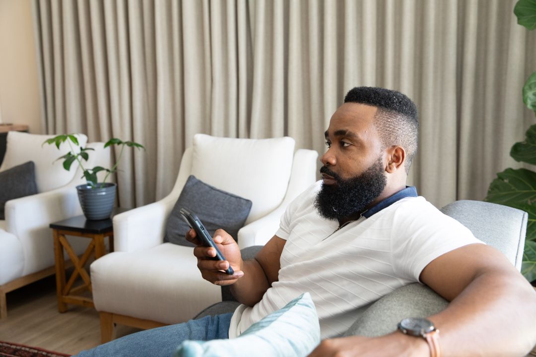 African American Man Relaxing at Home and Scrolling Smartphone