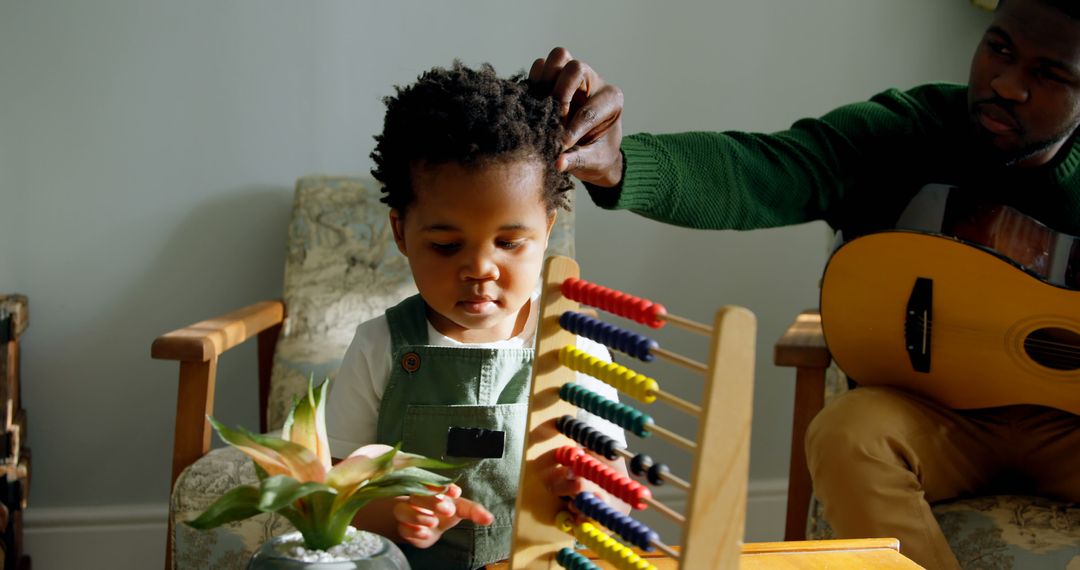 Toddler Playing with Abacus While Father Plays Guitar - Free Images, Stock Photos and Pictures on Pikwizard.com