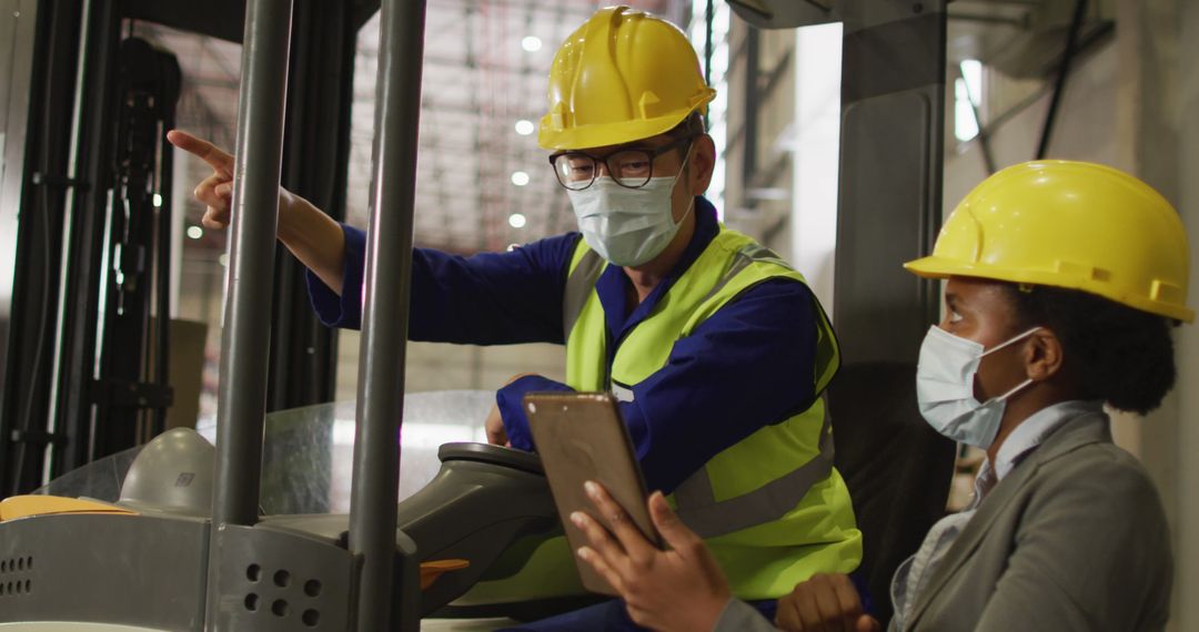 Industrial Workers Collaborating in Warehouse, Wearing Hard Hats and Masks - Free Images, Stock Photos and Pictures on Pikwizard.com