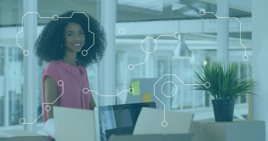 Smiling professional woman at modern open-plan desk with laptop, boxes and plant