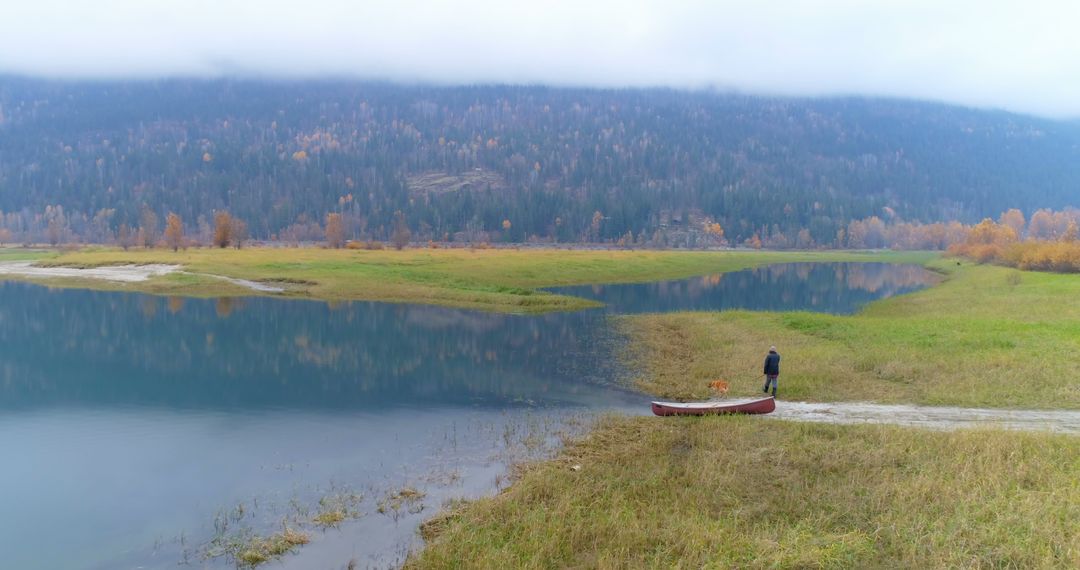 Solitary Man with Canoe by Serene Mountain Lake - Free Images, Stock Photos and Pictures on Pikwizard.com