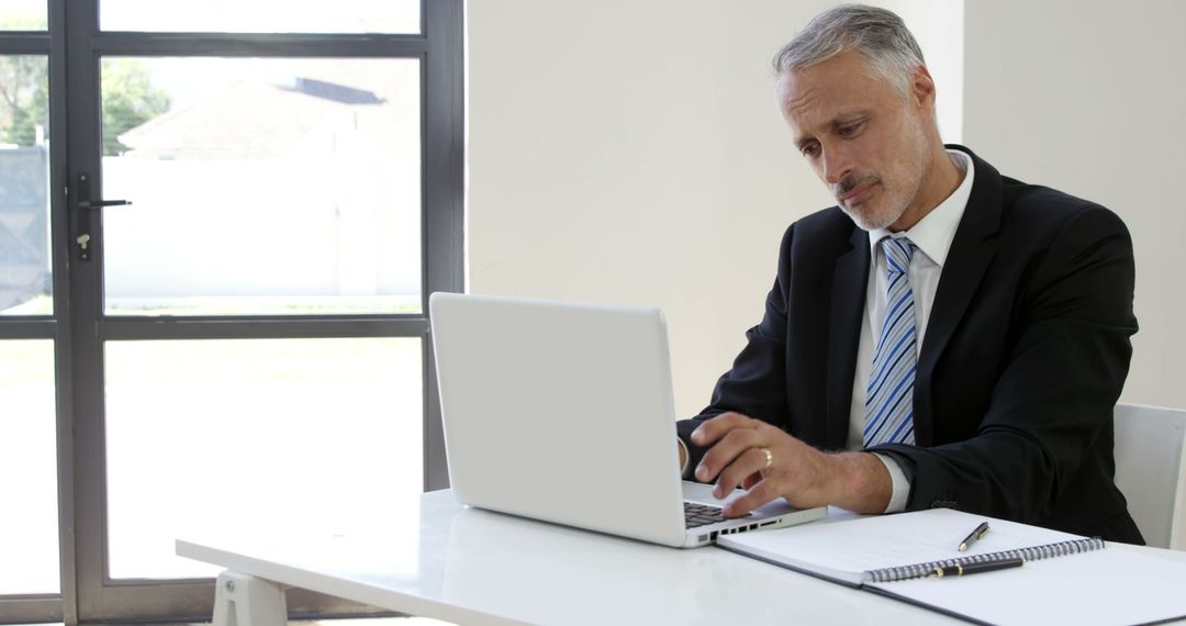 Mature Businessman Working on Laptop in Office with Natural Light - Free Images, Stock Photos and Pictures on Pikwizard.com