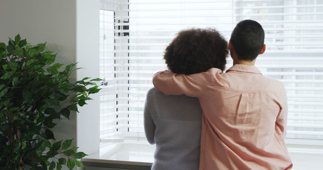 Diverse Couple Embracing by Window at Home