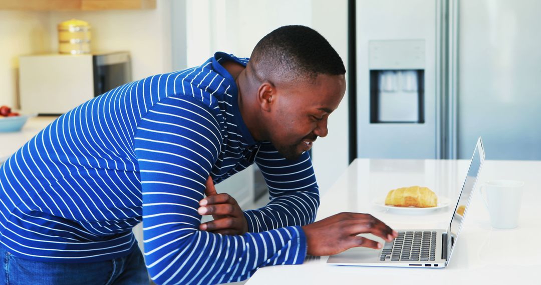 Smiling Man Using Laptop in Modern Kitchen - Free Images, Stock Photos and Pictures on Pikwizard.com