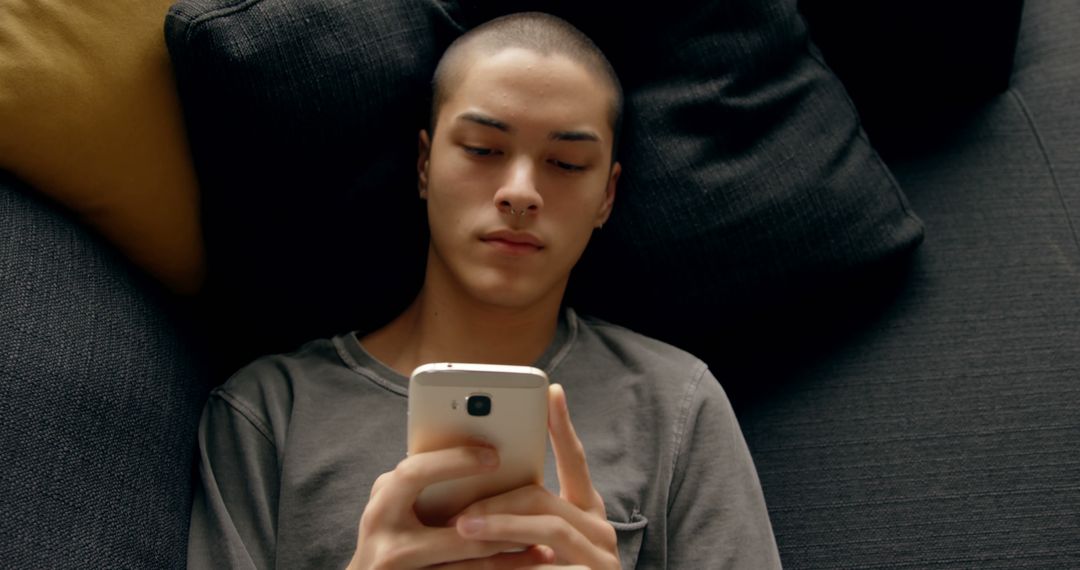 Young Man Lying on Couch Using Smartphone - Free Images, Stock Photos and Pictures on Pikwizard.com