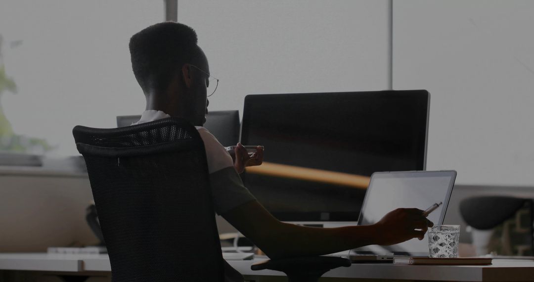 Office Worker Typing on Laptop While Enjoying Coffee