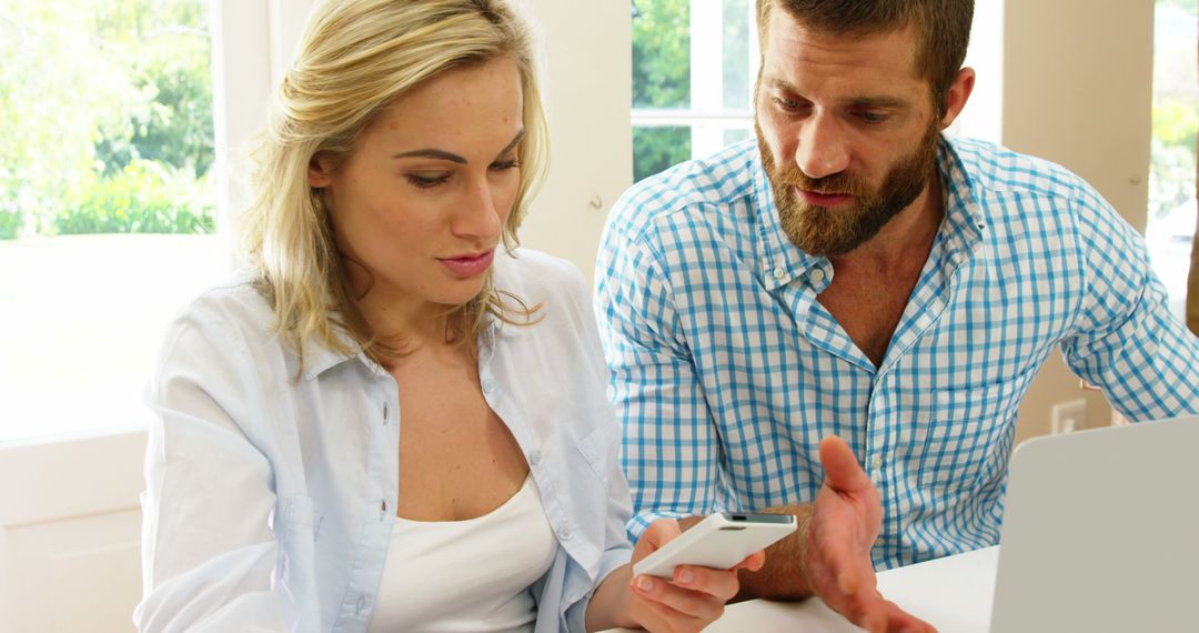 Couple Collaborating on Smartphone and Laptop at Home