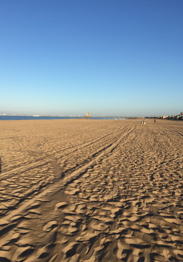 Empty Sandy Beach Stretching to Lifeguard Tower under Clear Blue Sky at Sunrise