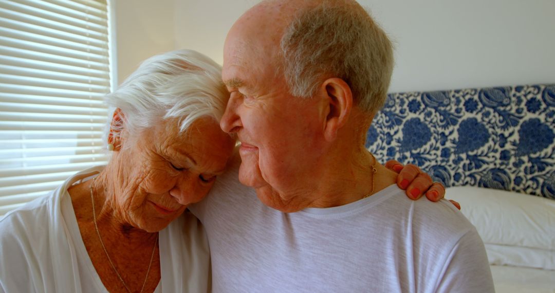 Elderly Couple Embracing in Bedroom with Natural Light - Free Images, Stock Photos and Pictures on Pikwizard.com