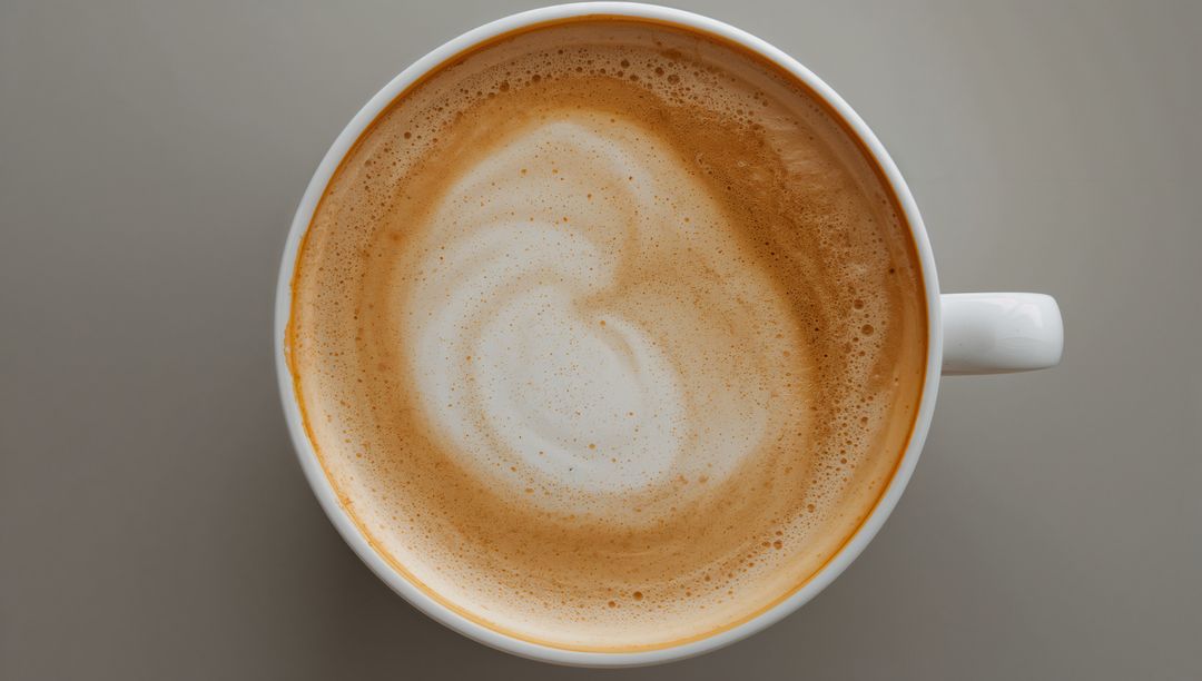 Overhead Latte with Creamy Milk Foam Swirl in White Ceramic Cup on Gray Minimal Tabletop