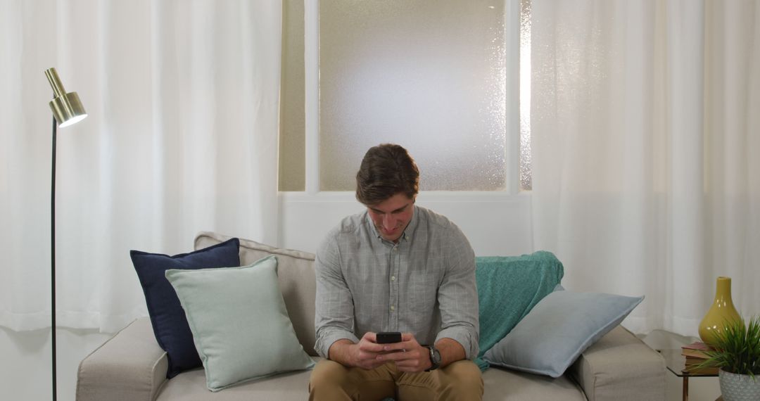 Man Using Smartphone Sitting on Couch in Living Room - Free Images, Stock Photos and Pictures on Pikwizard.com