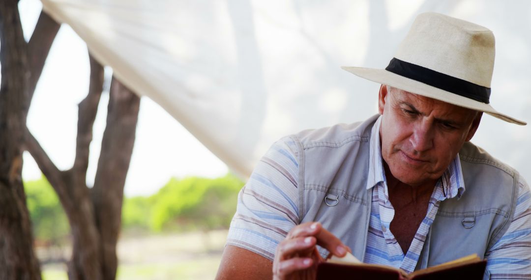 Middle-aged Man Reading Book Outdoors in Relaxed Atmosphere - Free Images, Stock Photos and Pictures on Pikwizard.com