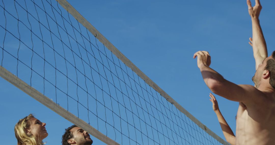 People playing beach volleyball against blue sky - Free Images, Stock Photos and Pictures on Pikwizard.com