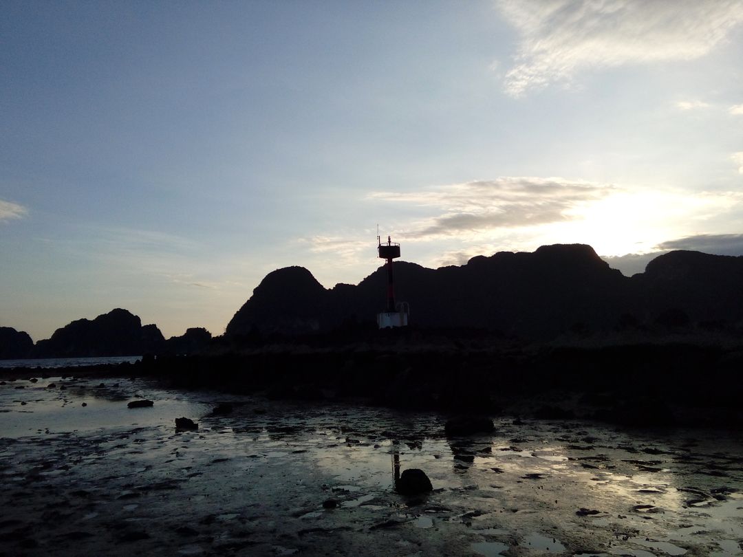 Serene Lighthouse Silhouette at Low Tide During Sunset - Free Images, Stock Photos and Pictures on Pikwizard.com