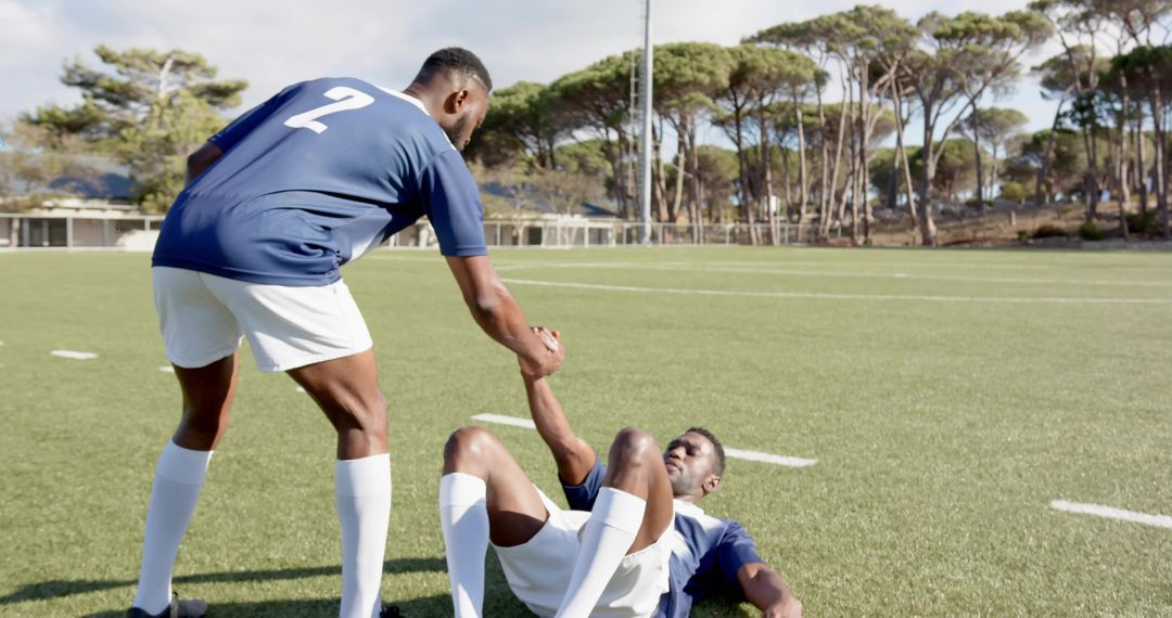 Helping Teammate Up on Soccer Field Showing Teamwork, Sportsmanship and Athletic Support