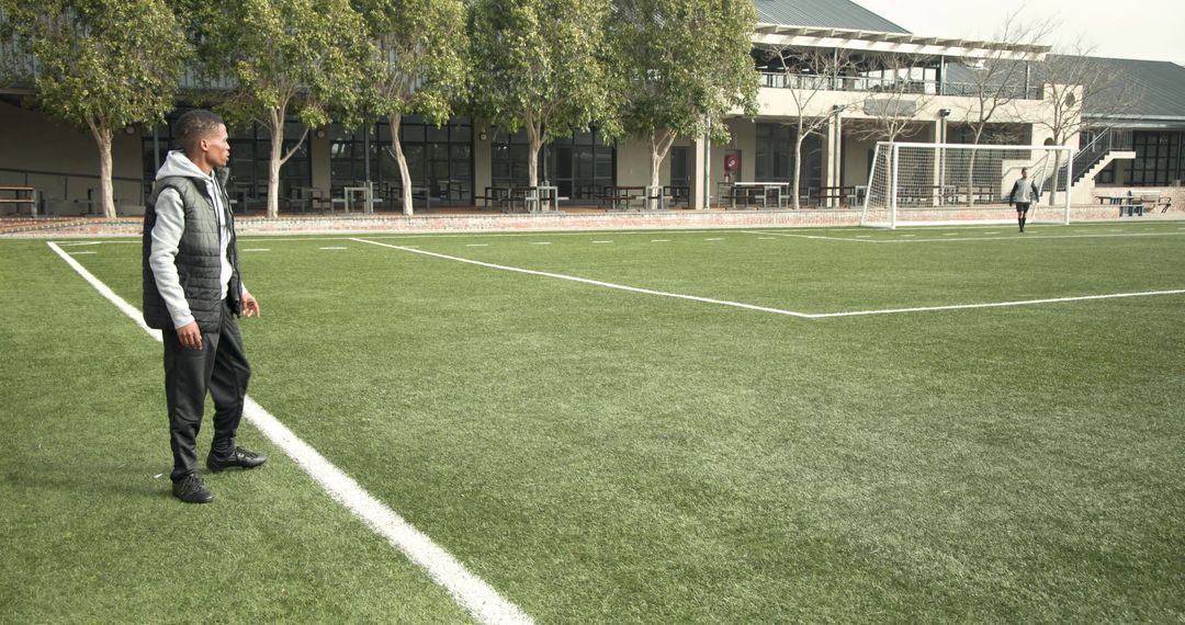 Coach Instructs on Soccer Field with Practicing Players in Background