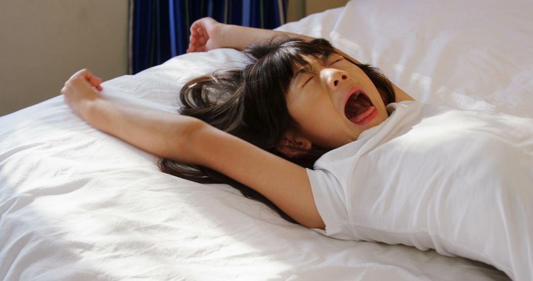 Young Girl Yawning and Stretching on Bed in Morning Light - Free Images, Stock Photos and Pictures on Pikwizard.com