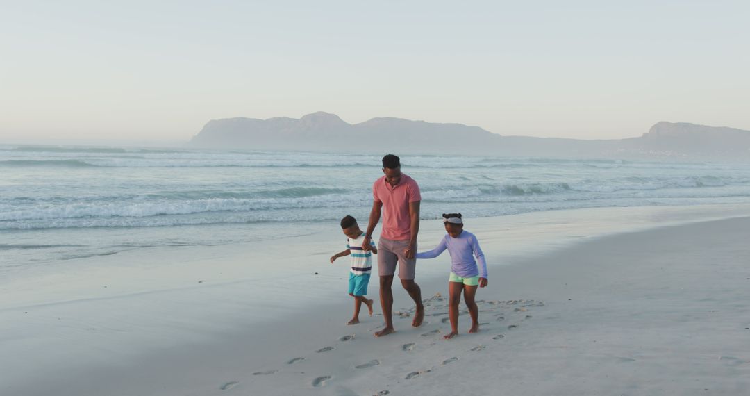 Father with Two Children Walking on Sandy Beach at Sunrise - Free Images, Stock Photos and Pictures on Pikwizard.com