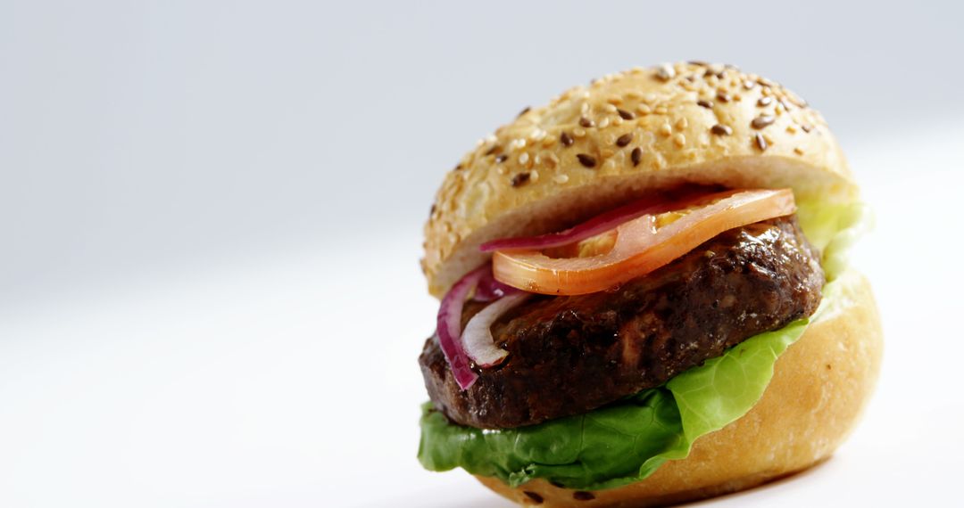 Close-up of Juicy Beef Burger with Lettuce, Tomato, and Onion on a Sesame Seed Bun - Free Images, Stock Photos and Pictures on Pikwizard.com