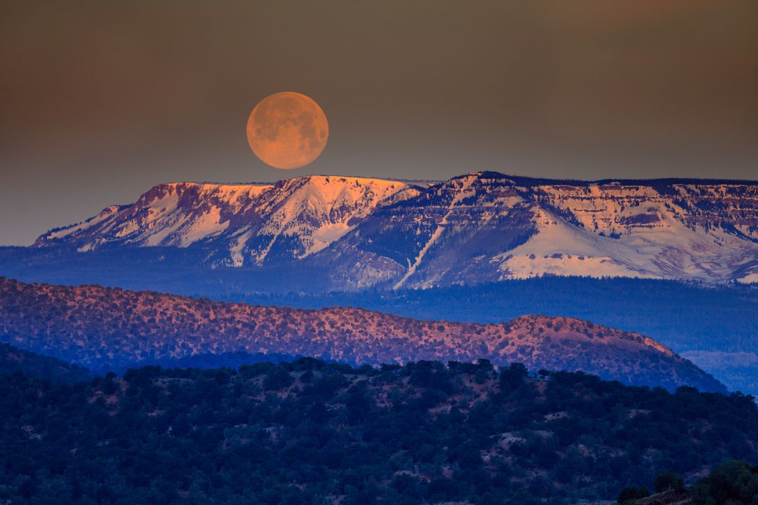 Full Moon Rising Over Snow-Capped Mountain Range at Dusk