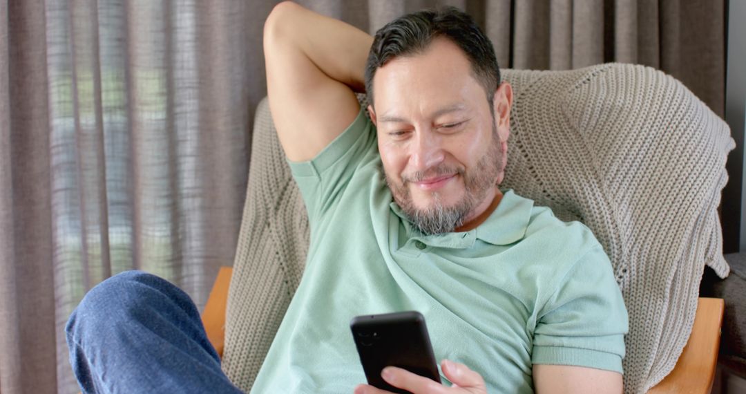 Asian Man Relaxed at Home Using Smartphone on Casual Day