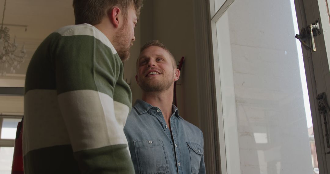 Two Young Men Smiling and Talking Near Window in Casual Setting - Free Images, Stock Photos and Pictures on Pikwizard.com