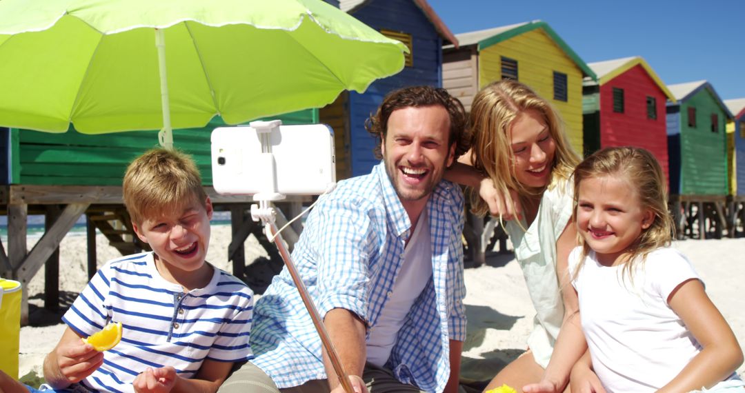 Family Enjoying Beach Day Taking Selfie Near Colorful Beach Huts - Free Images, Stock Photos and Pictures on Pikwizard.com