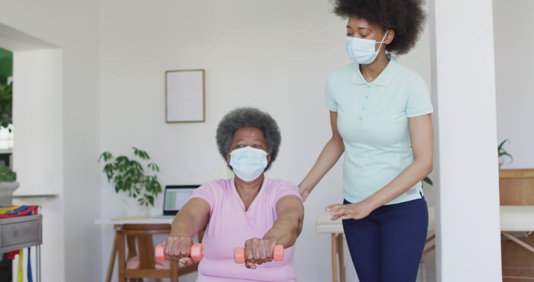 Senior woman exercising with nurse, wearing masks during home physical therapy session - Free Images, Stock Photos and Pictures on Pikwizard.com