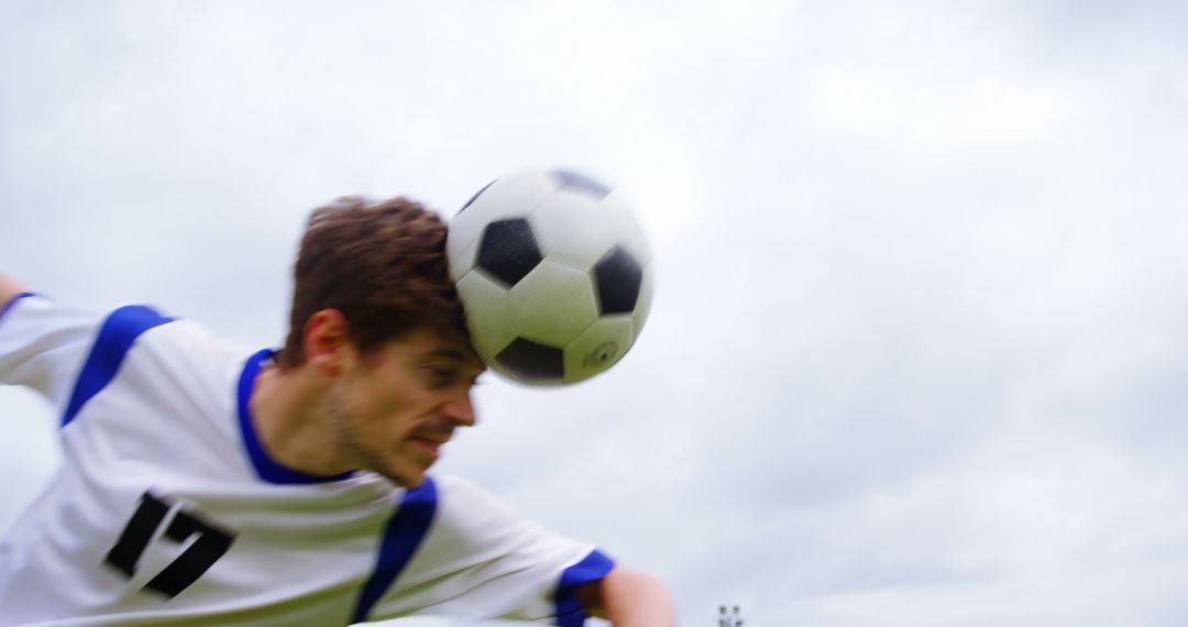 Soccer Player Heading Ball During Game Cloudy Sky Background - Free Images, Stock Photos and Pictures on Pikwizard.com